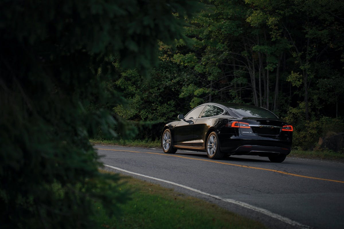 An electric car silently driving down a country lane.  Level of engine noise vs pedestrian safety is often talked about when discussing electric cars pros and cons. 