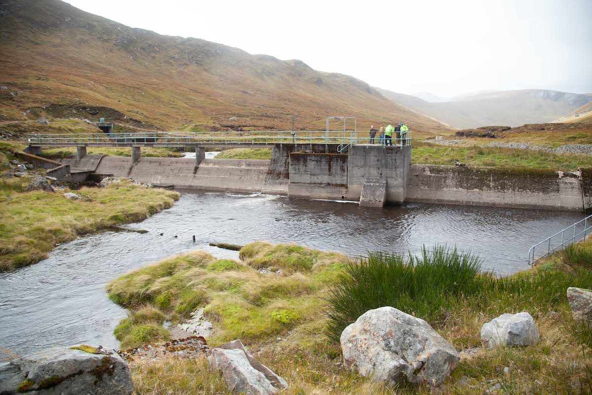 A river and dam on a misty day in Scotland. Dams can cause problems for wild Atlantic salmon migration