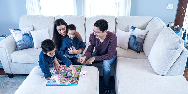 A family of 4 maximizing space in their small home but using an ottoman as a board game table.