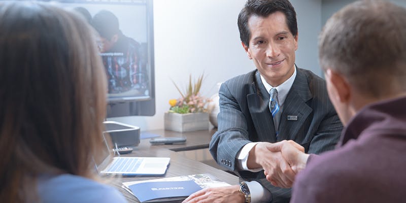 A mortgage broker and 2 borrowers discussing earnest money in an office