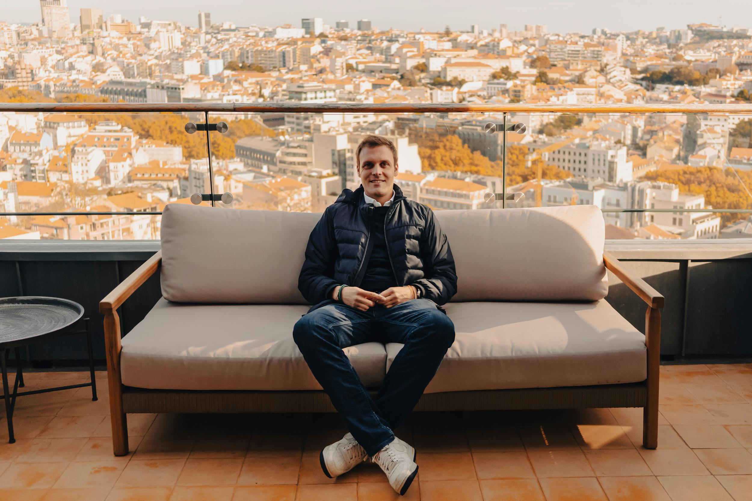 young man sitting on a sofa with a view of cascais in the background