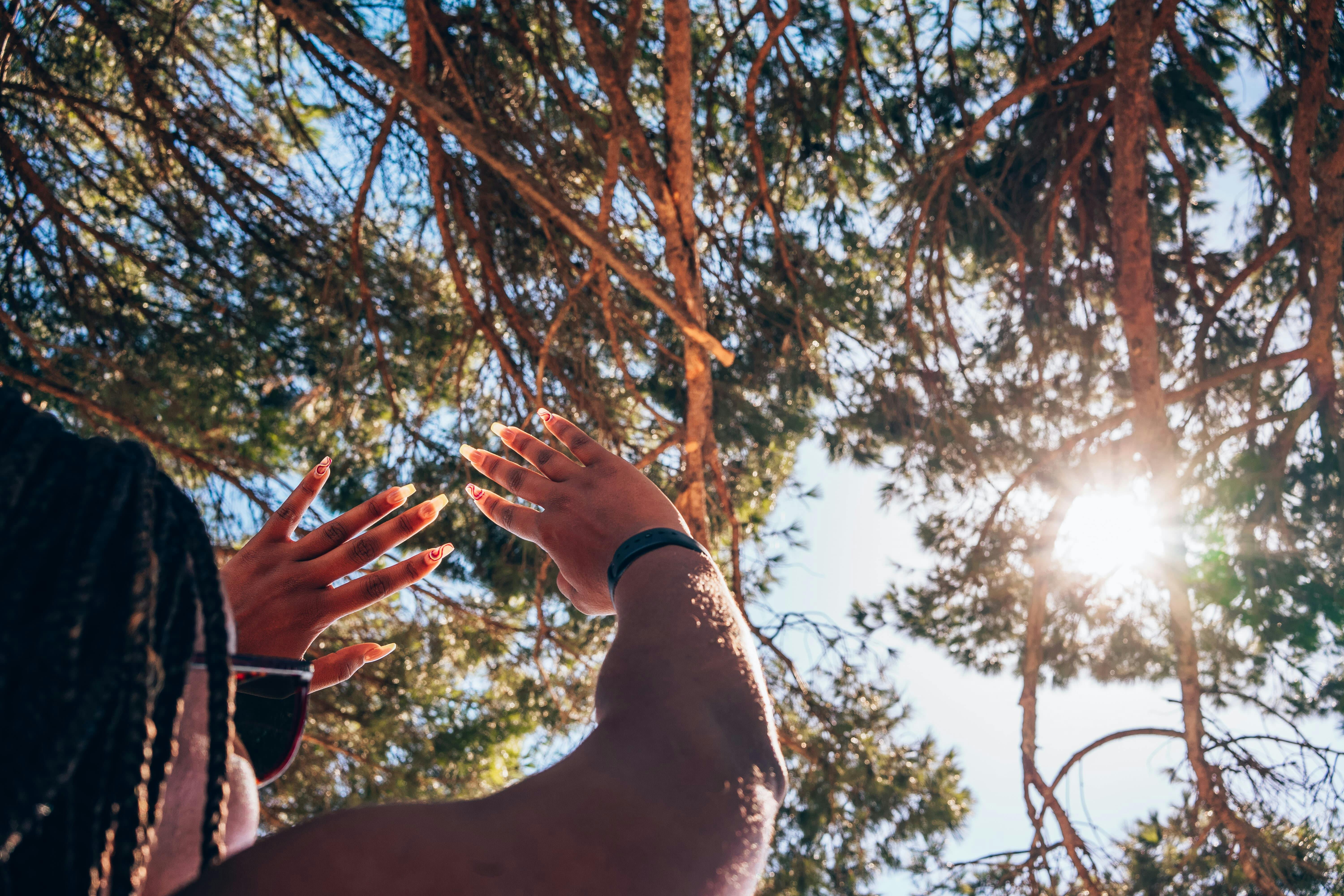 Woman raising her hands to shield her face from the direct sunlight.