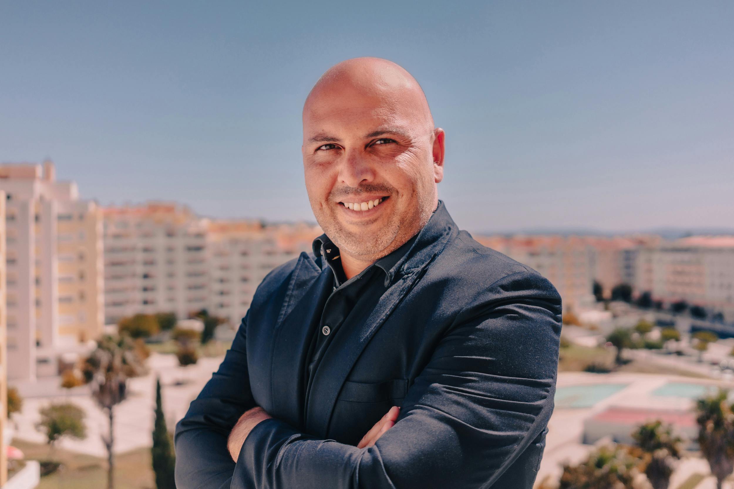 A bald man in a suit posing with a smile