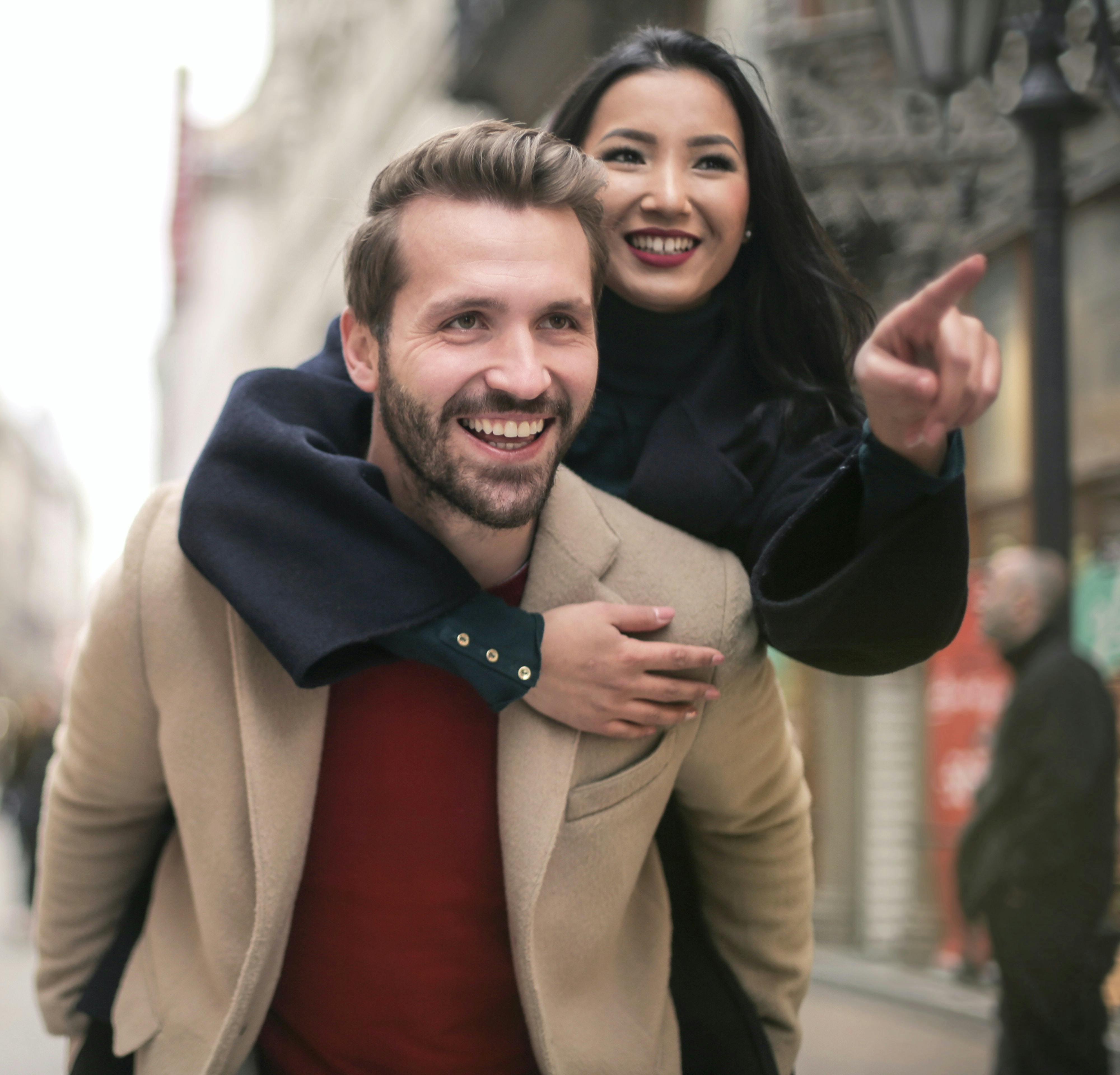 Young couple smiling, with the man holding the woman on his back