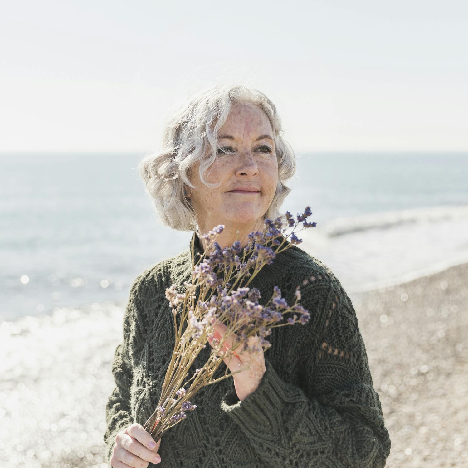 Mulher idosa com flores na praia