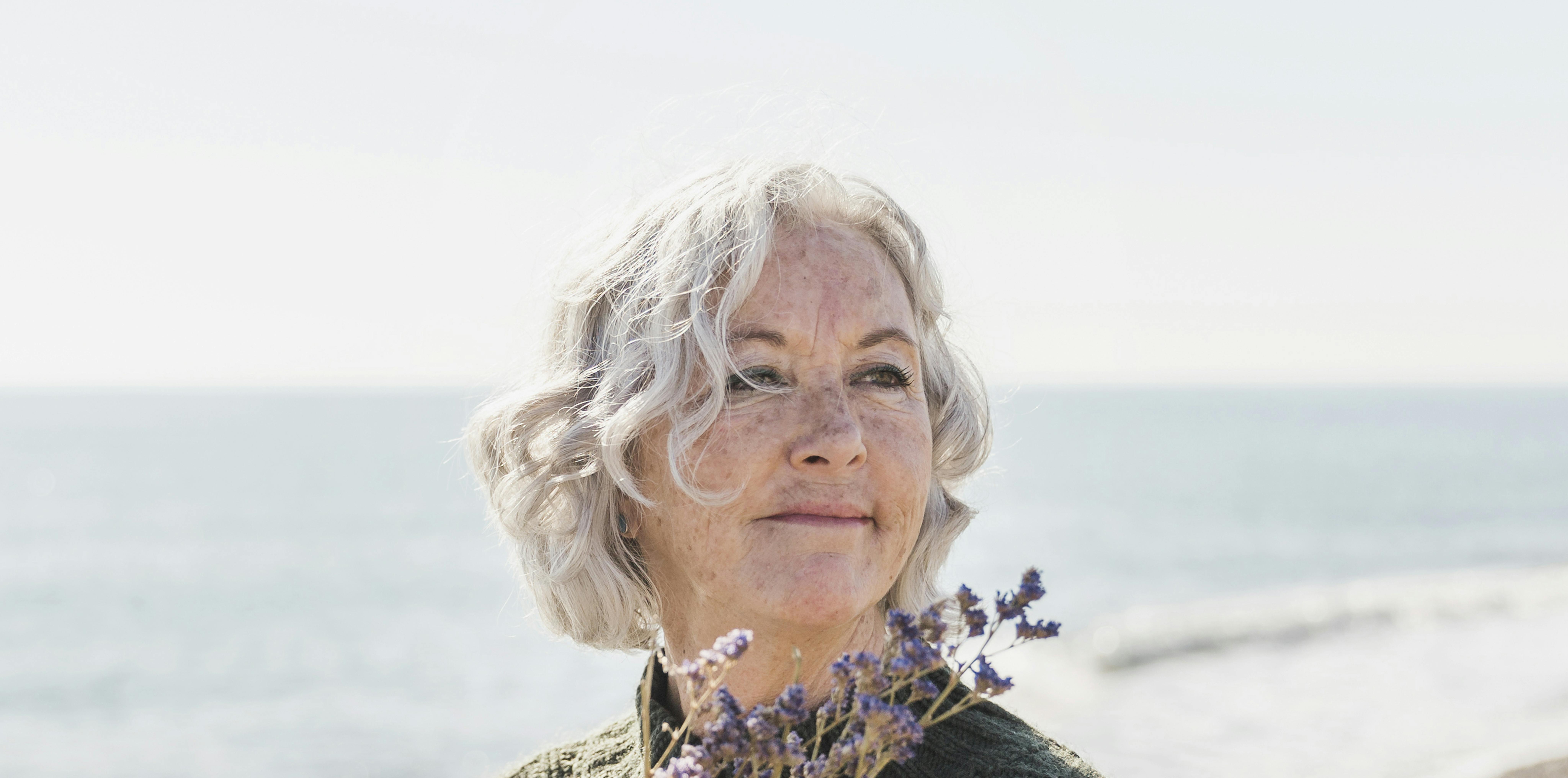 Mulher idosa com flores na praia