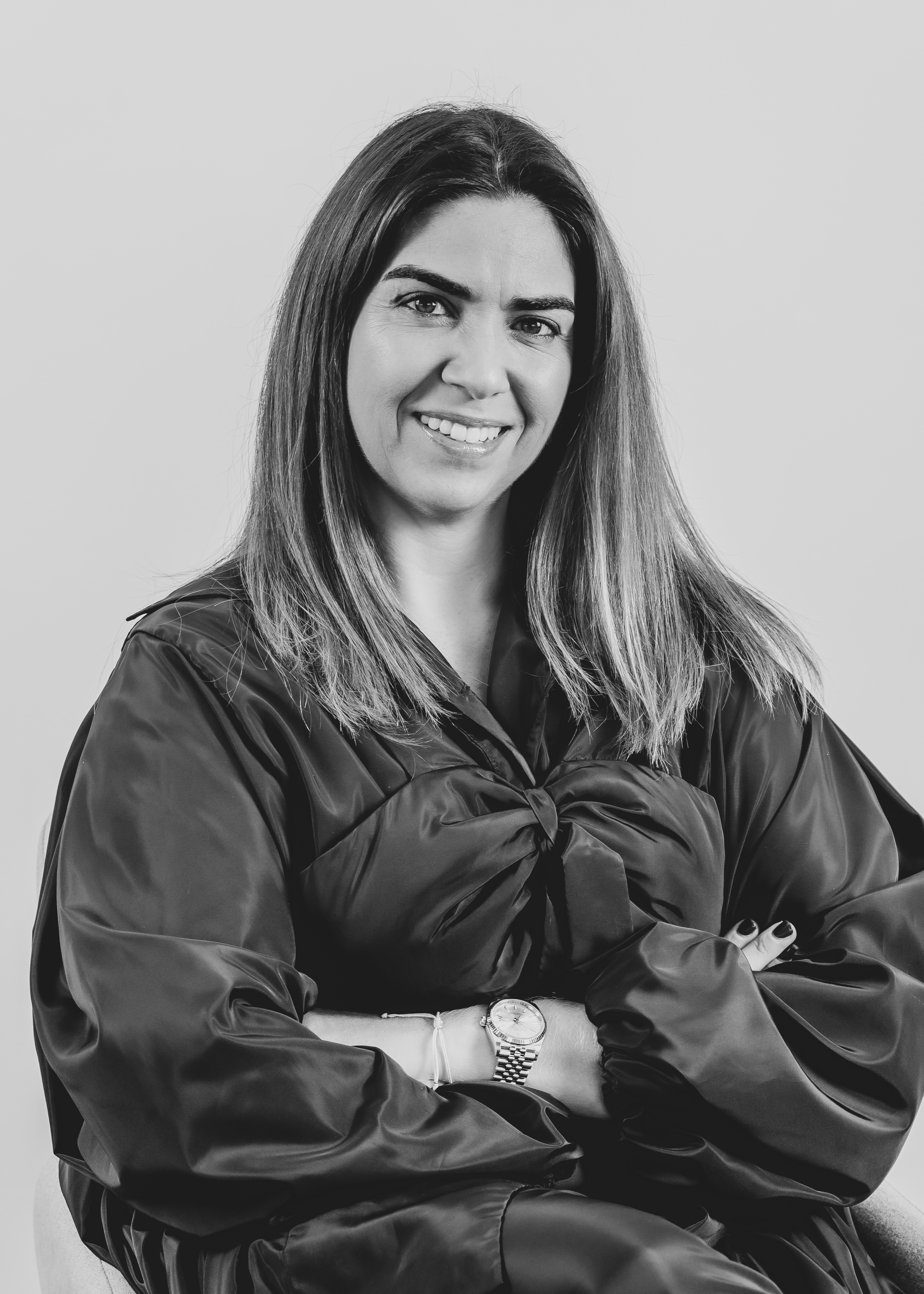Black and white photo of Raquel Roque, a woman with long dark hair, smiling warmly, dressed in a black dress.