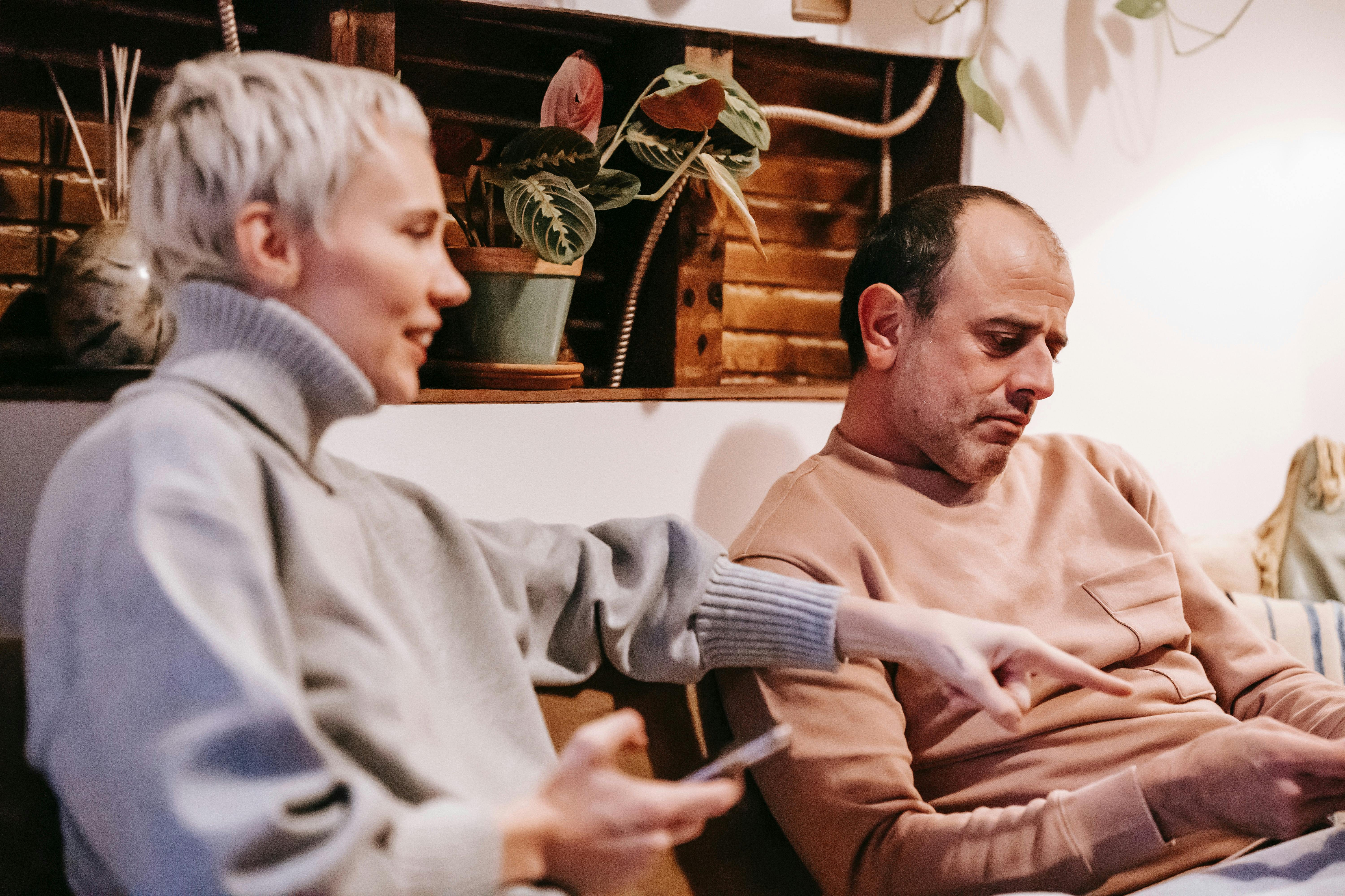 Blond woman pointing down at the tablet the dark hair man next to her is holding