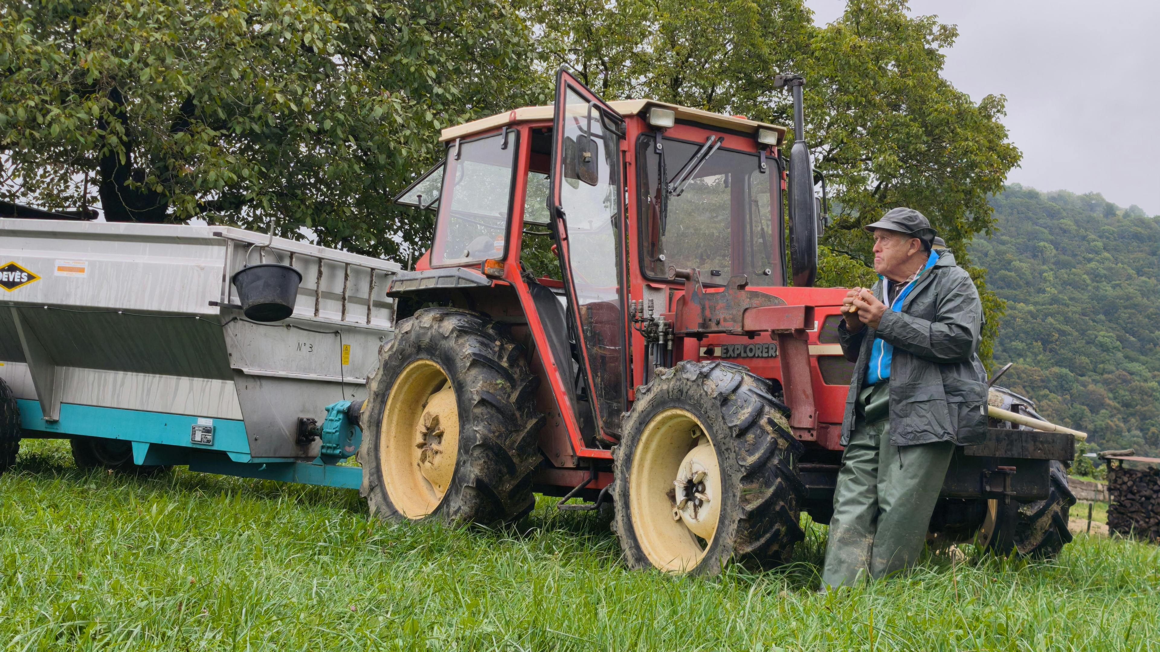 un vieux qui mange son sandwuich accoudé au tracteur