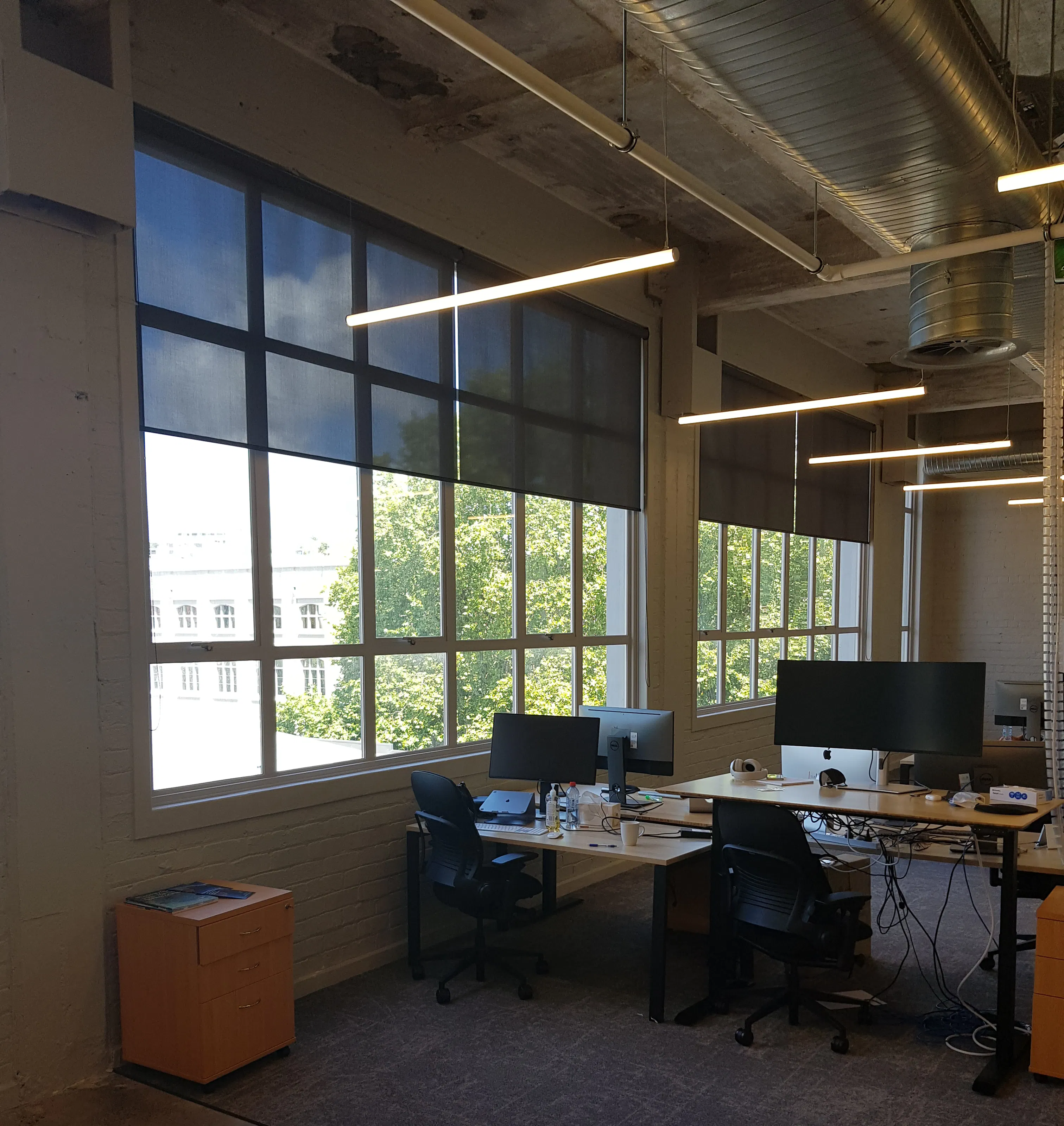 Black sunscreen roller blinds in modern office