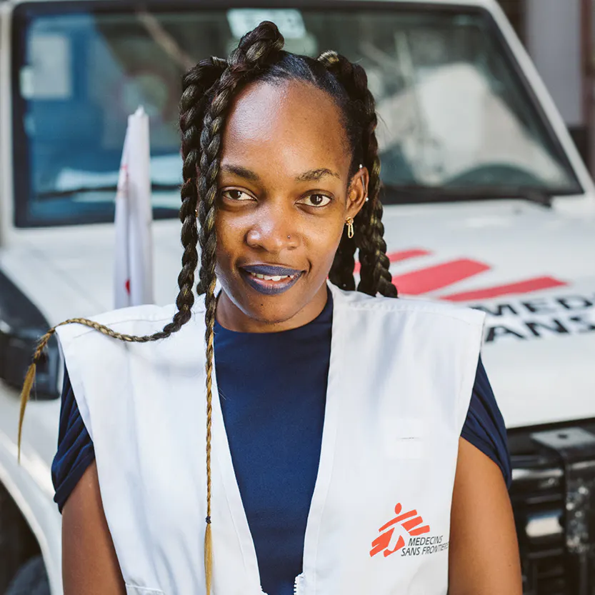 MSF team member standing in front of a Médecins Sans Frontières vehicle.
