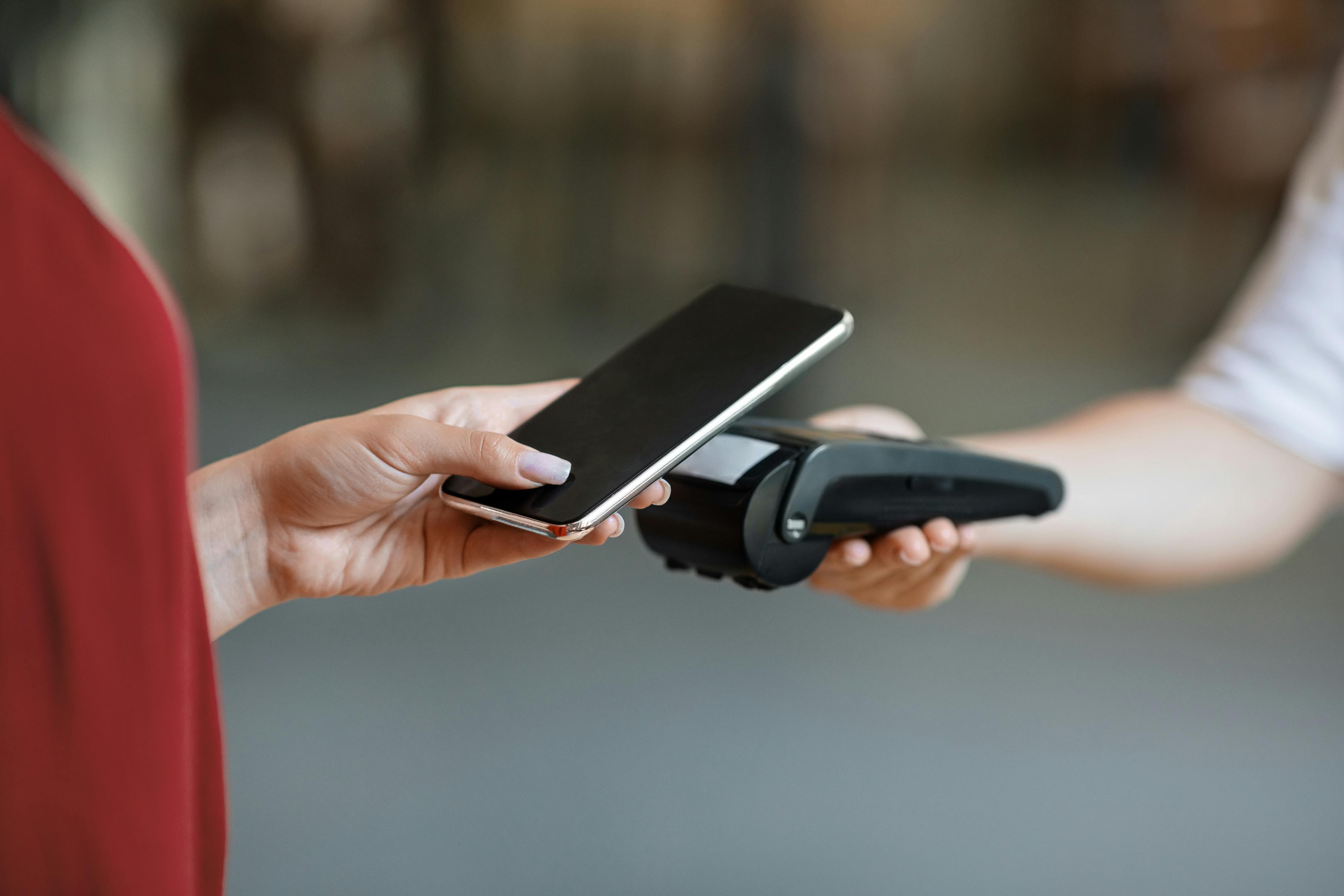 Technologie NFC. Femme méconnaissable faisant un paiement sans contact avec son smartphone à un terminal