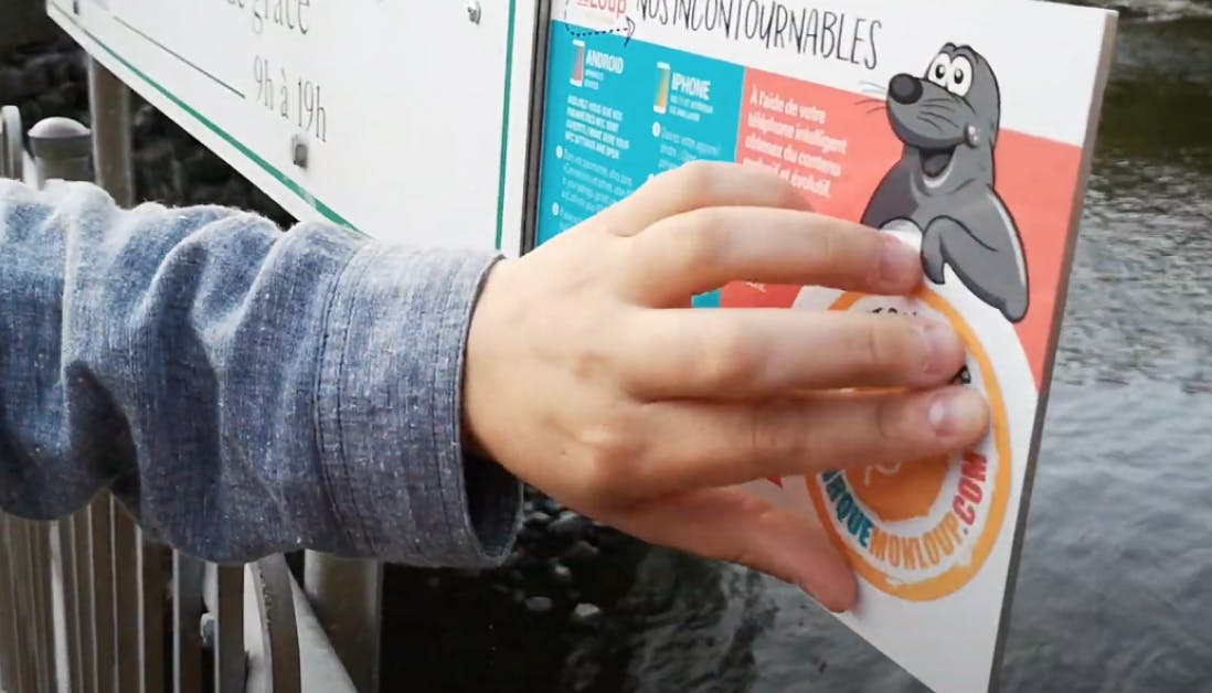 a hand shows the NFC tag of a poster