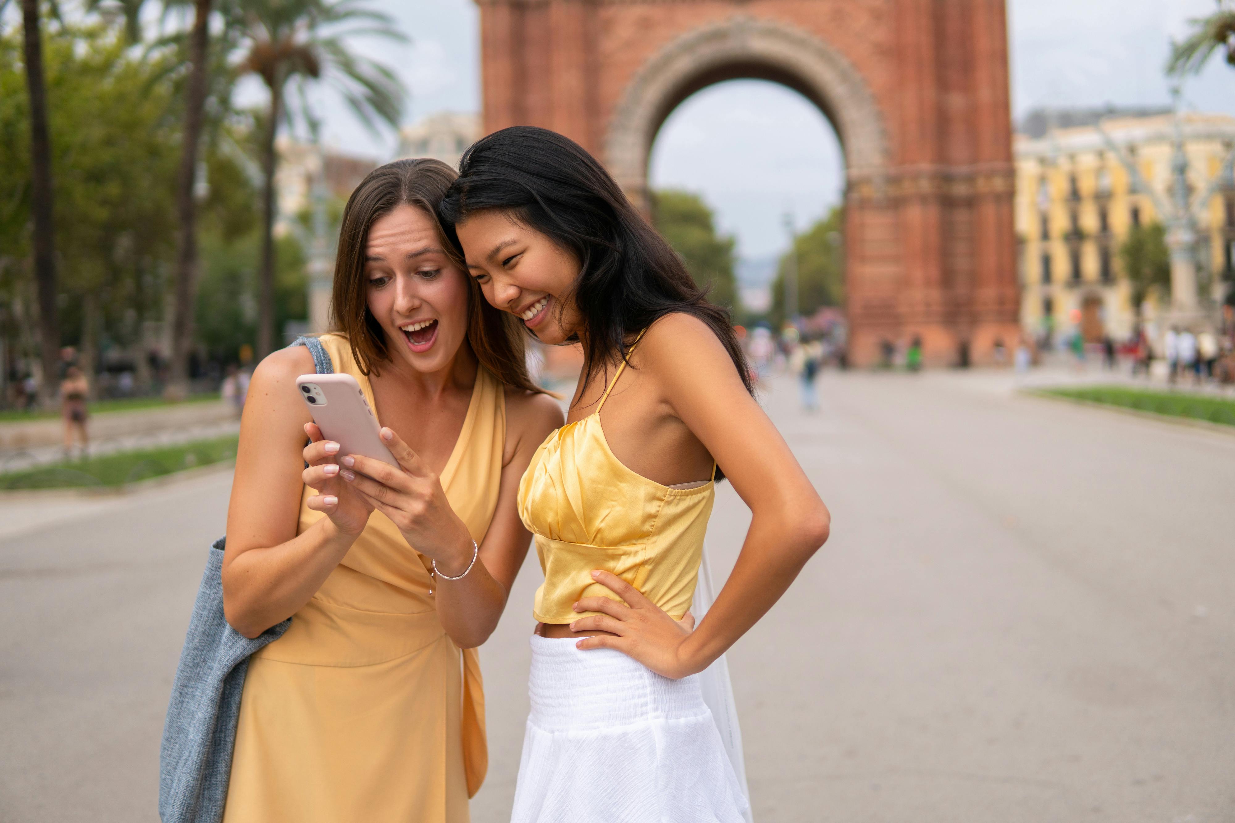Excited diverse girlfriends using smartphone in city