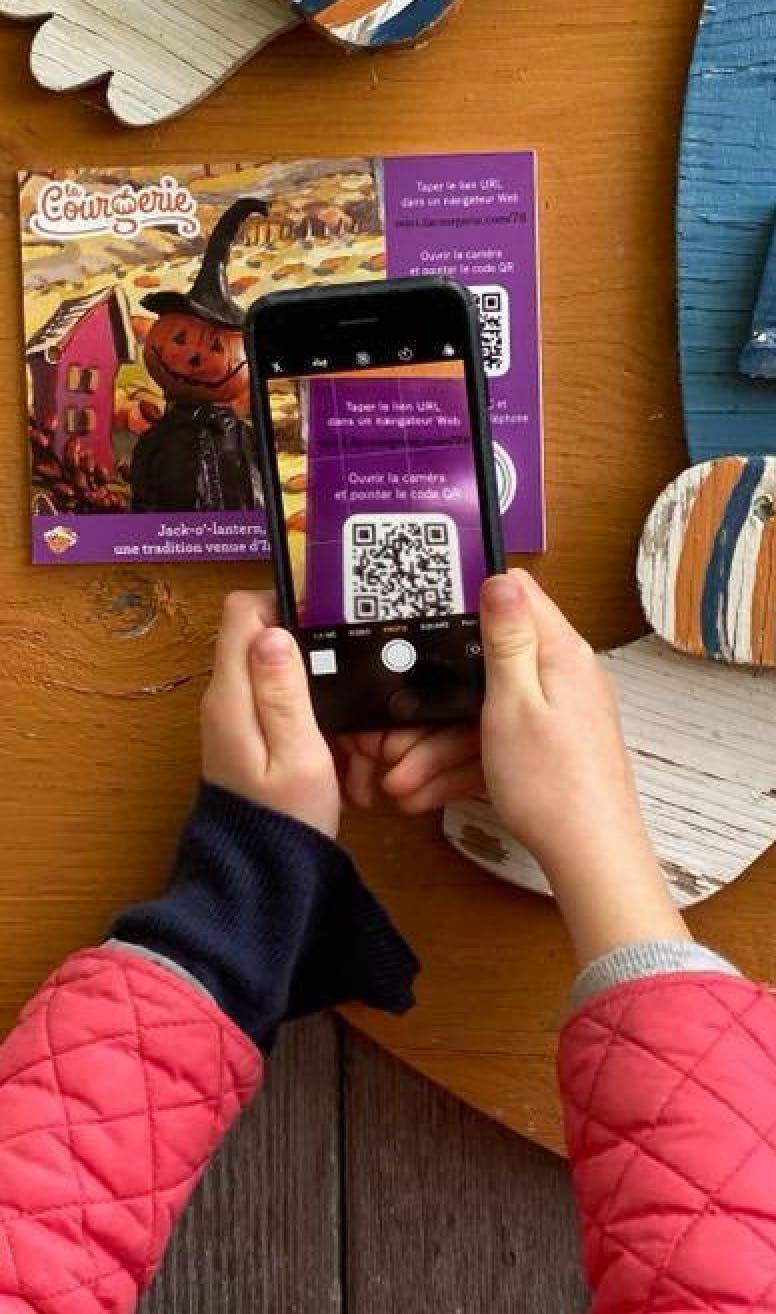 Un enfant qui lit le code QR d'une affichette de la Courgerie