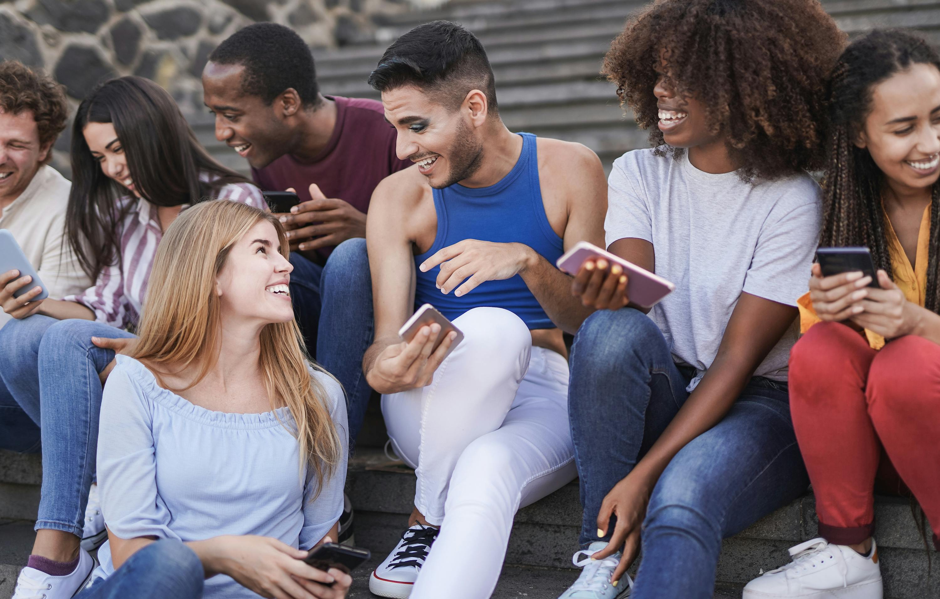 Des personnes multiraciales s'amusent ensemble dans la ville tout en utilisant un téléphone portable