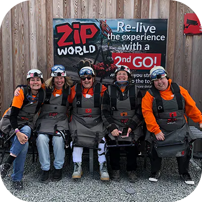 Charity event participants smiling whilst preparing to go zip lining. 