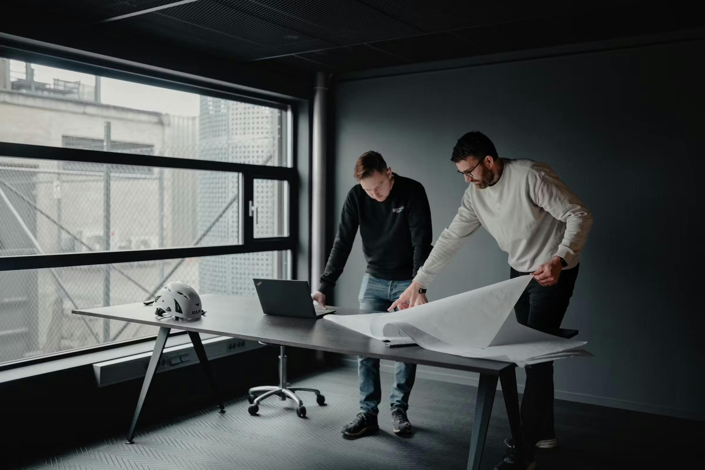 två medarbetare vid skrivbord med ritningar