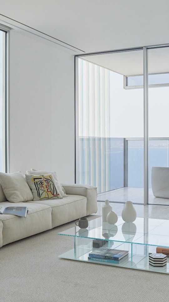 Sunny contemporary living room with bay windows overlooking a terrace with an outdoor lounge