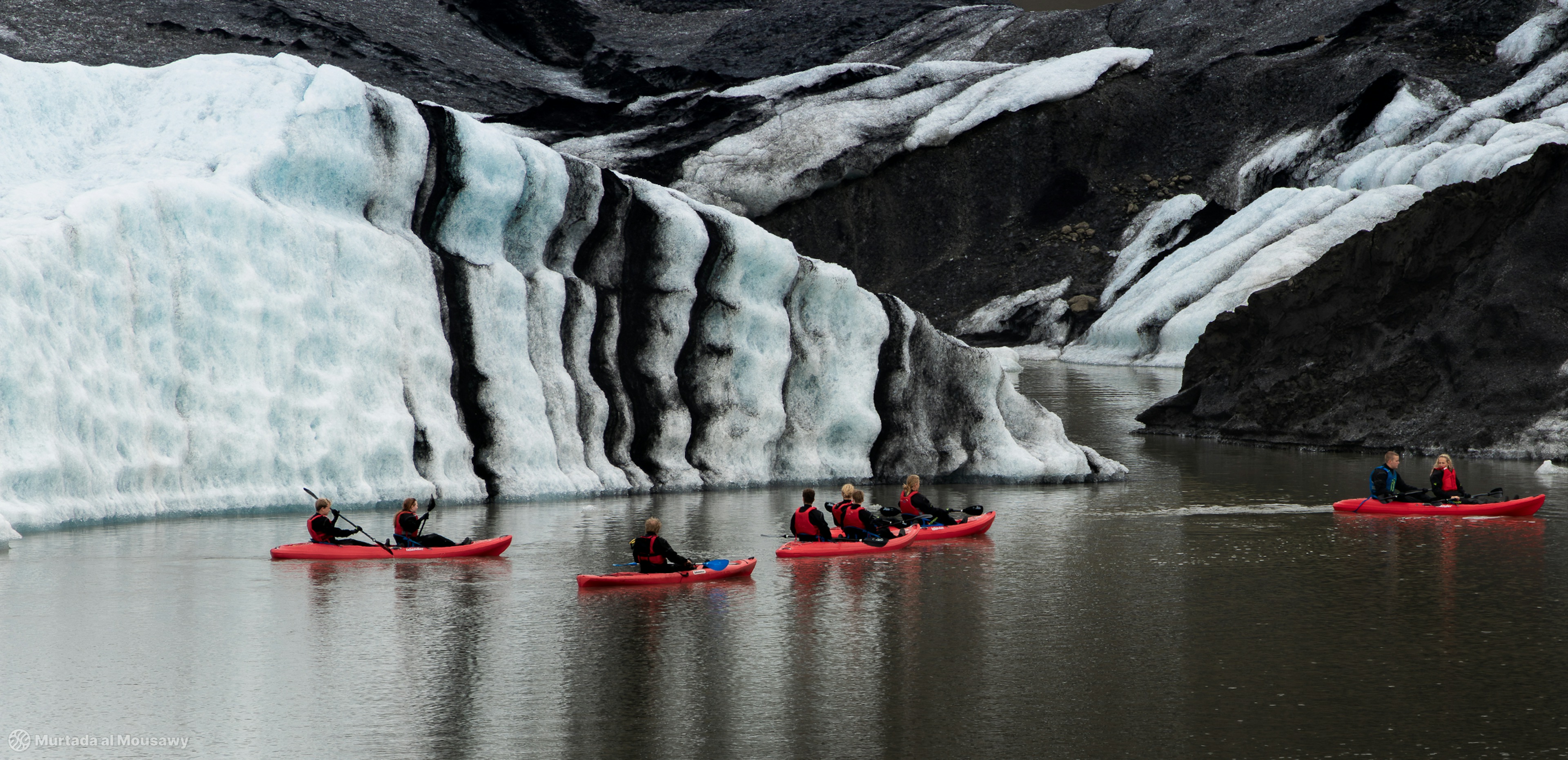 A group of canoers in between glacial ice in a river in Iceland.