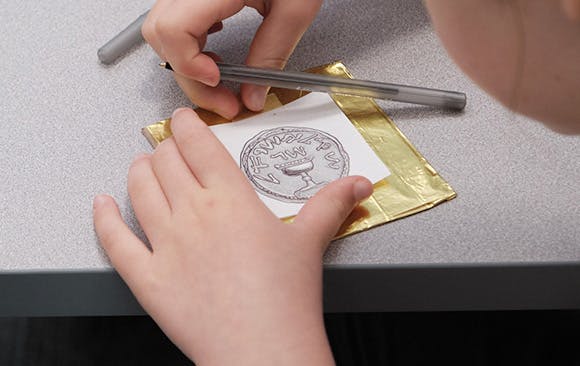 Girl creating a coin impression on foil