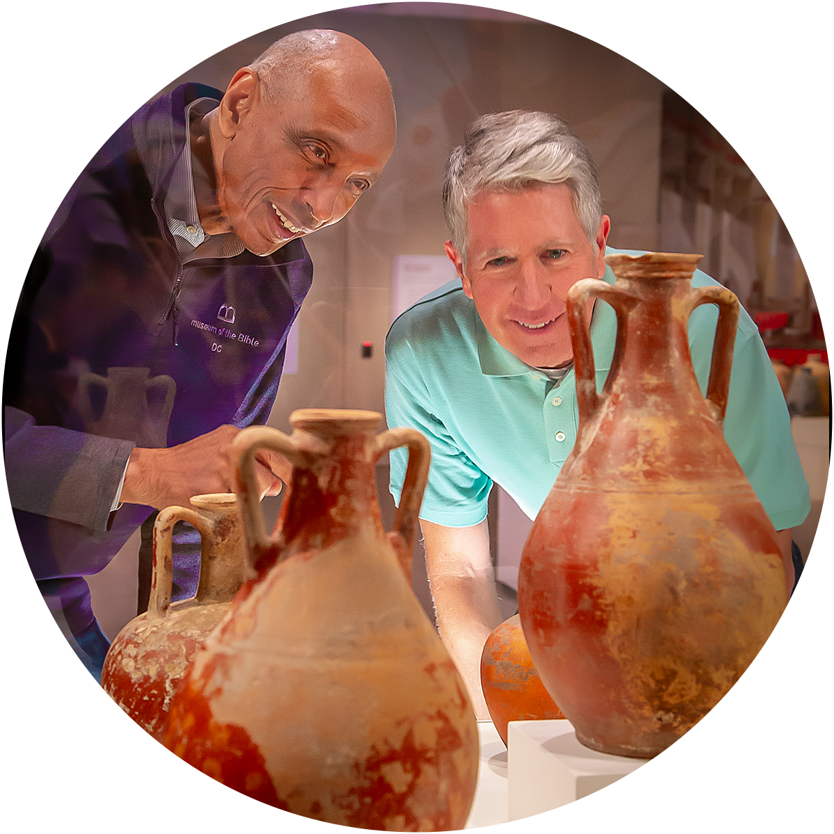 Two men view two ancient clay vases in a museum case.