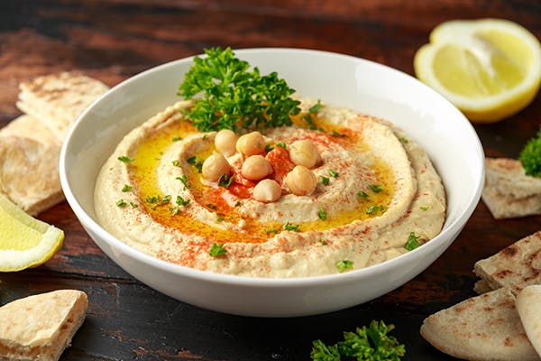 Bowl of hummus surrounded by lemon slices and pita at Manna Bites 