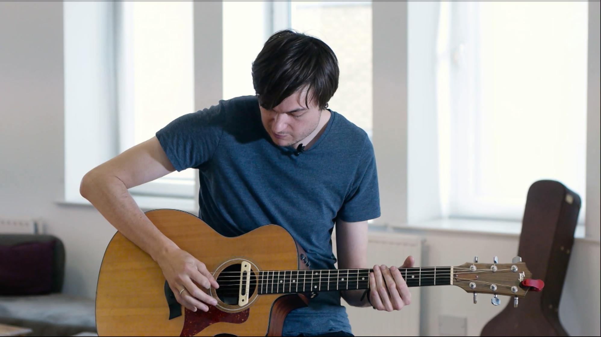 A man playing and tuning an acoustic guitar