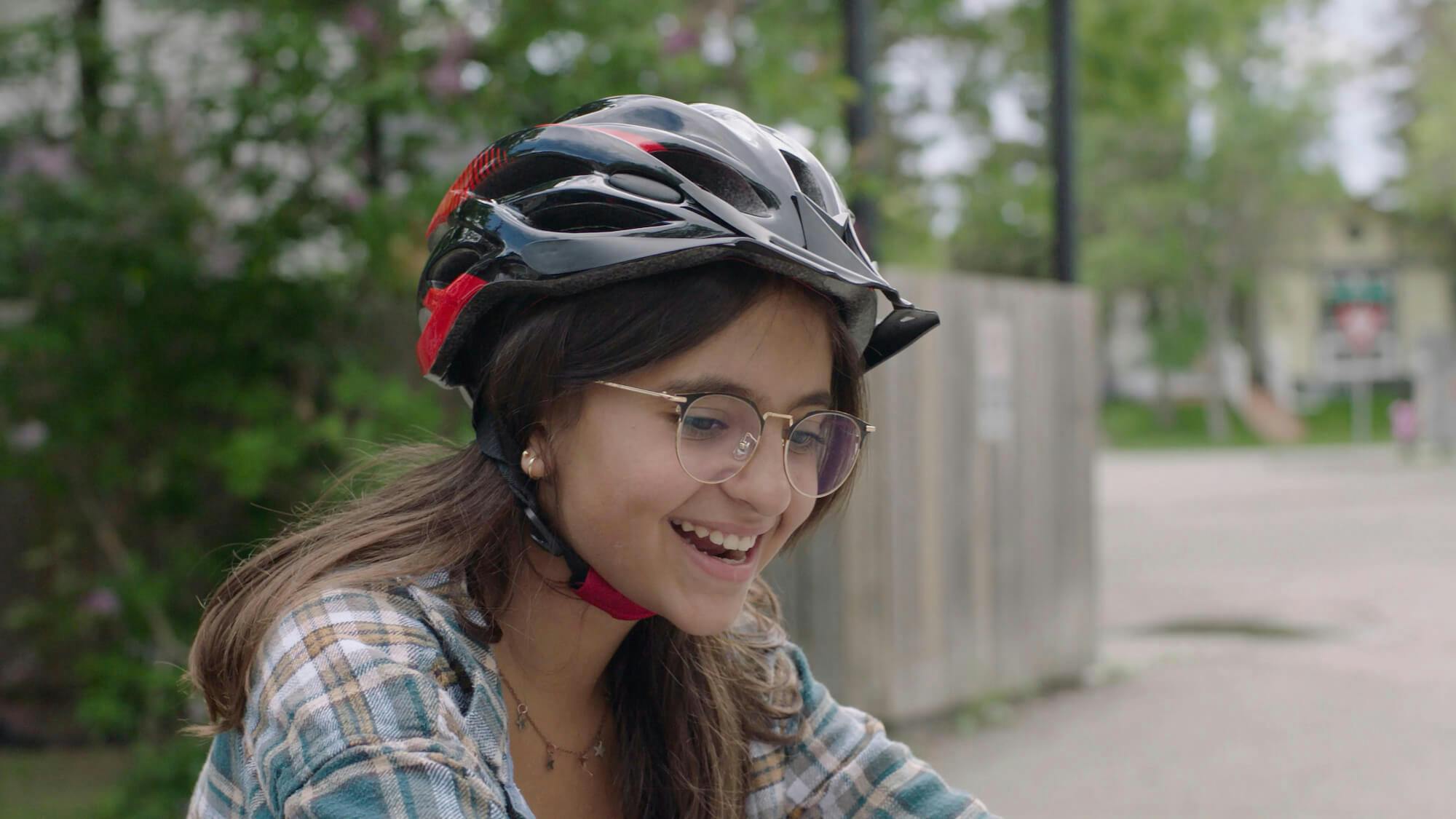 A girl wearing a bike helmet smiles.