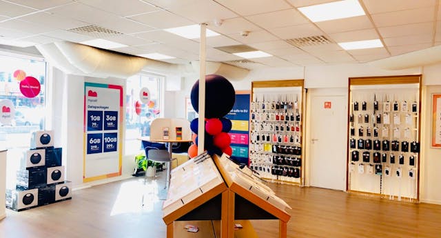 Interior of a mobile phone shop with data package pricing displays, colourful balloons, and a wall of phone accessories.