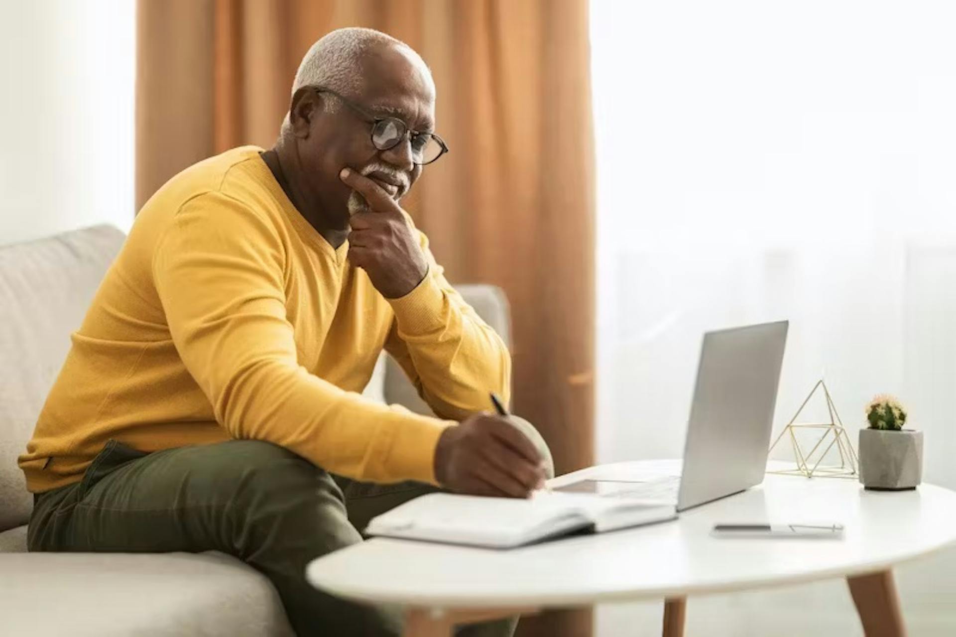 man on laptop looking at papers