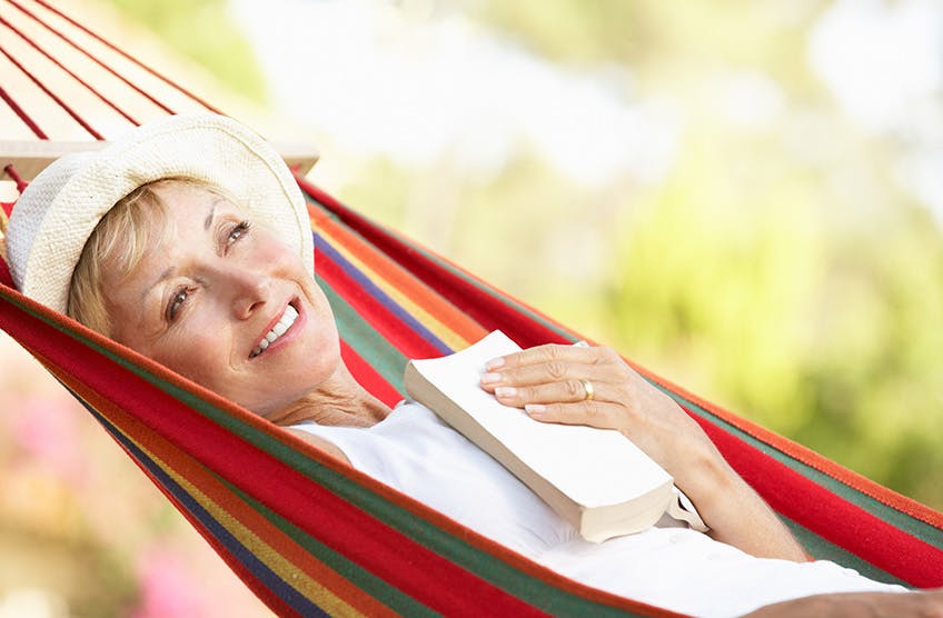 Woman smiling on a hammock with a book