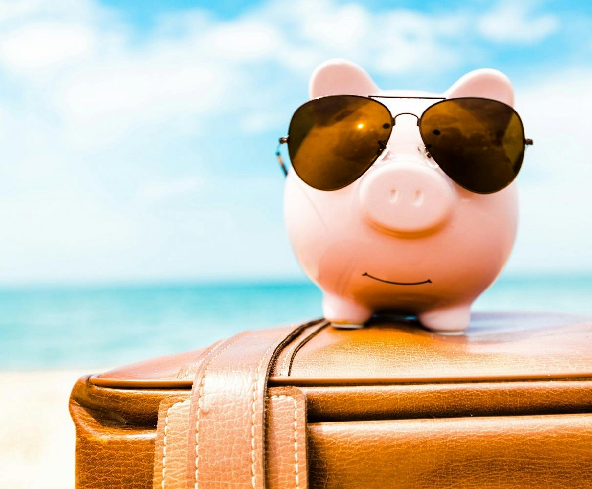 piggy bank with sunglasses on suitcase