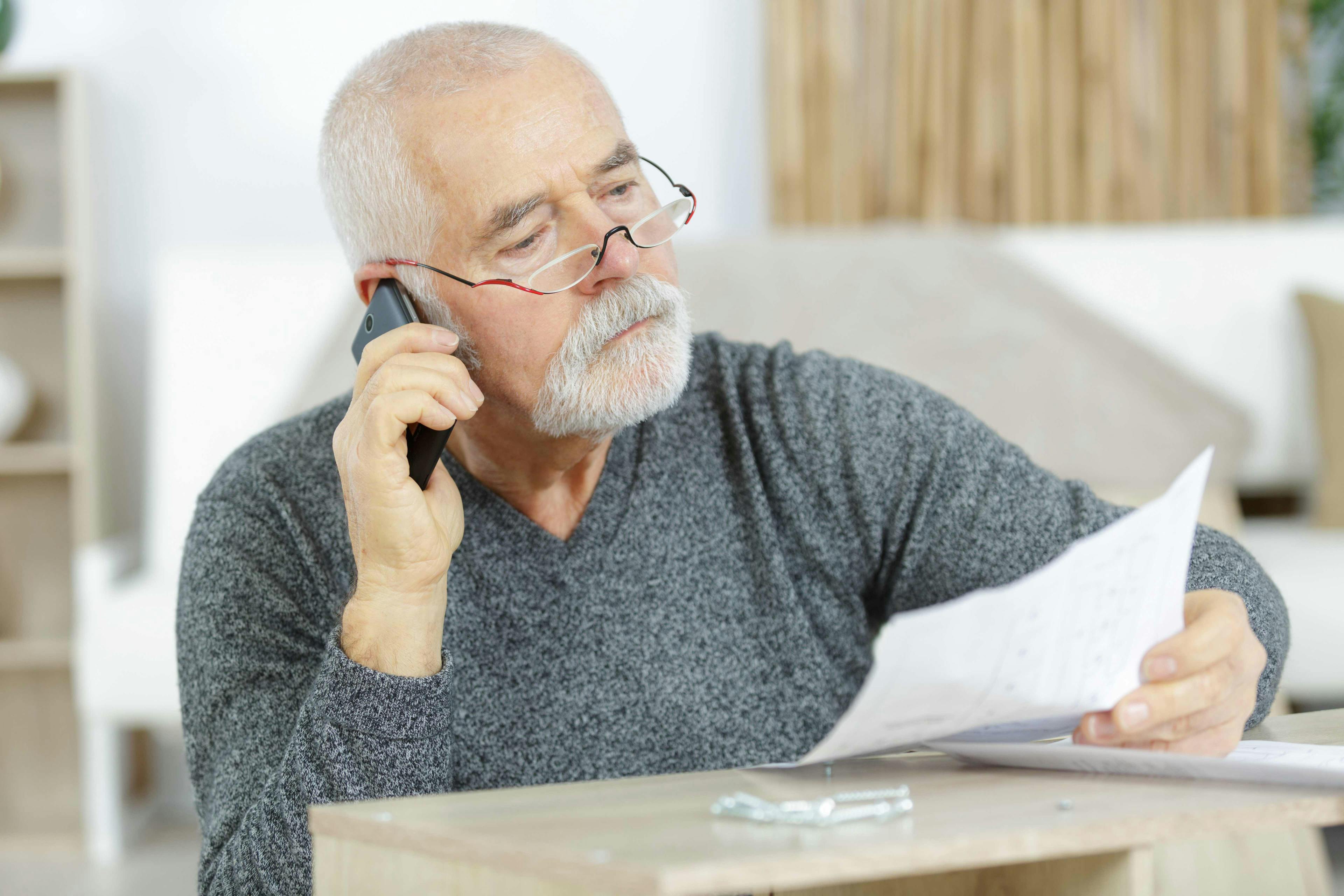 Man on phone holding a bill