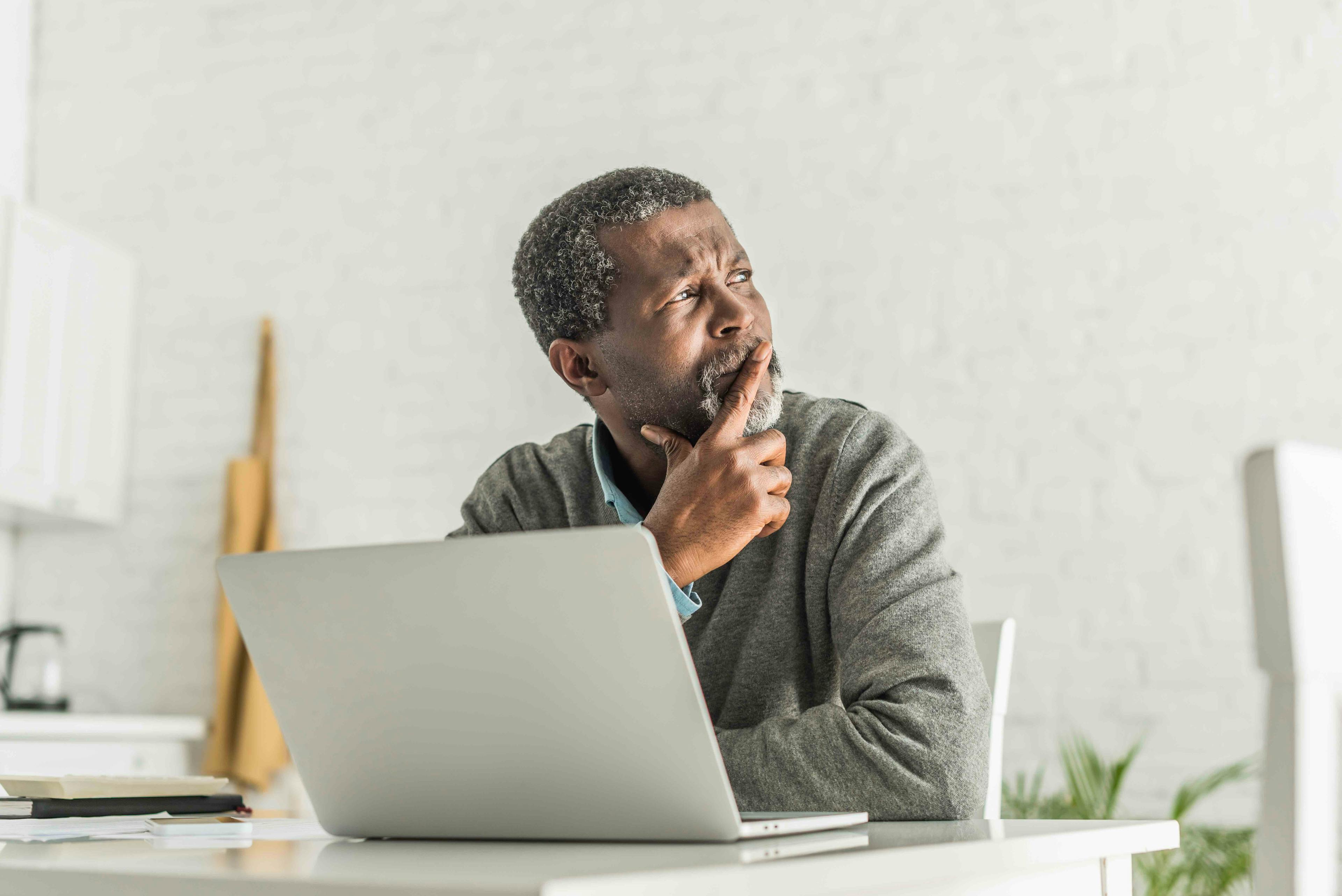 Man sitting at computer looking pensively to the side