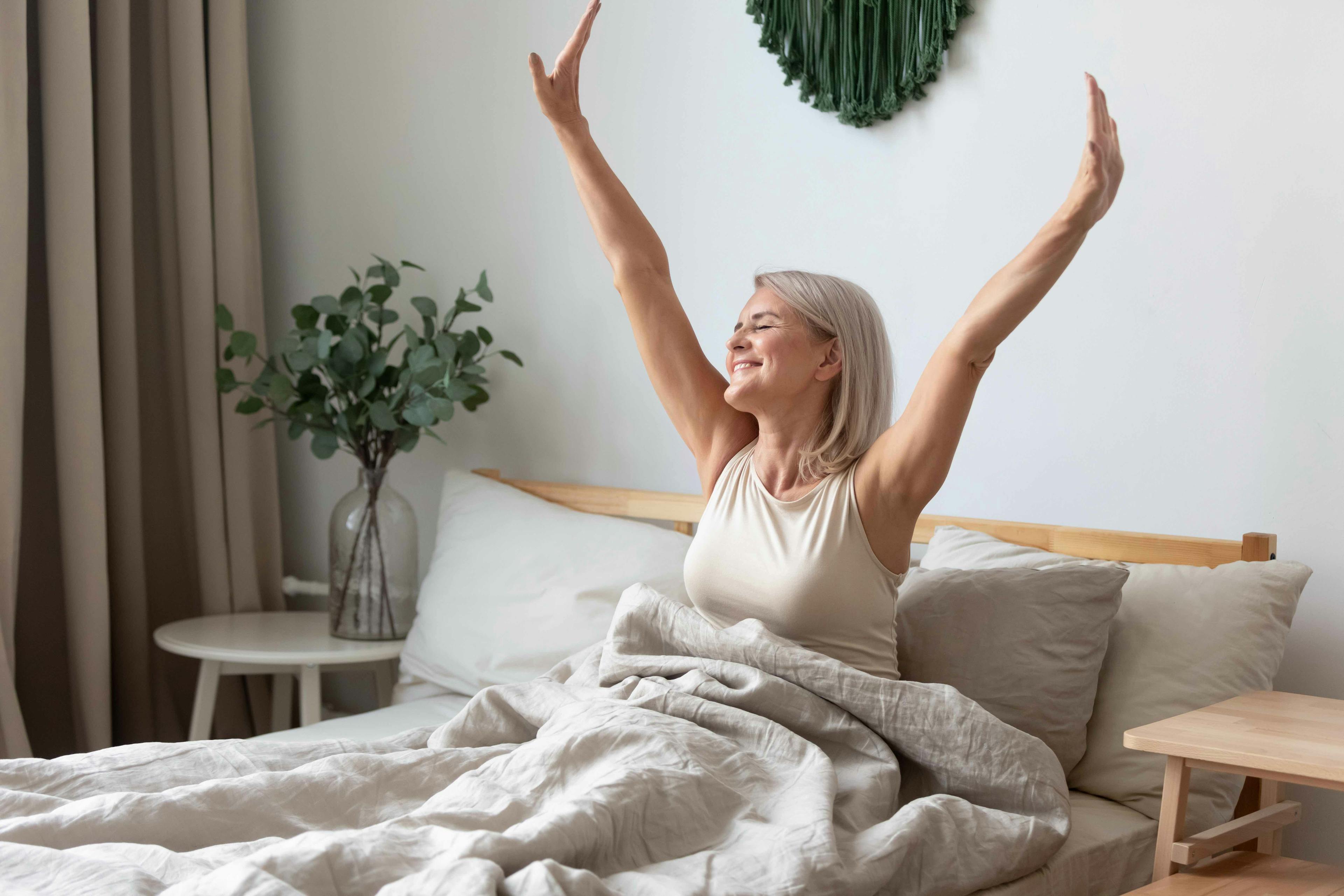 Woman waking up happy in bed