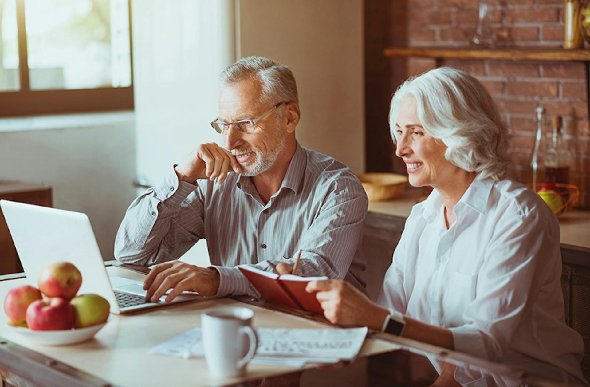 man and woman looking at their laptop sitting in their kitchen