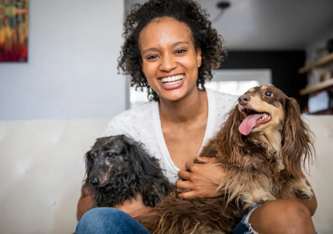 Femme qui sourit avec ses deux Teckel dans les bras