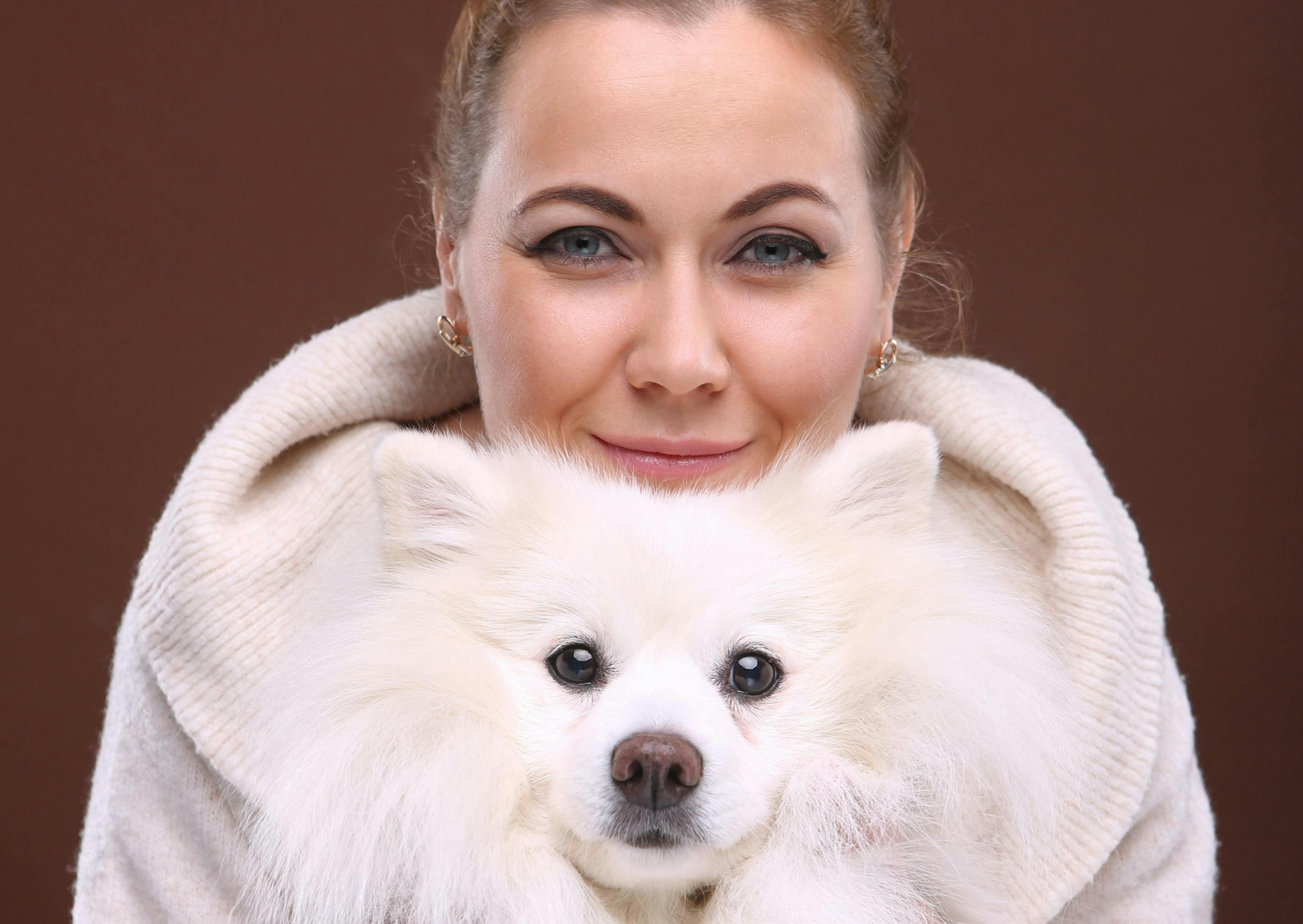 Spitz Japonais qui regarde l'objectif avec sa maitresse qui pose la tête sur sa tête 