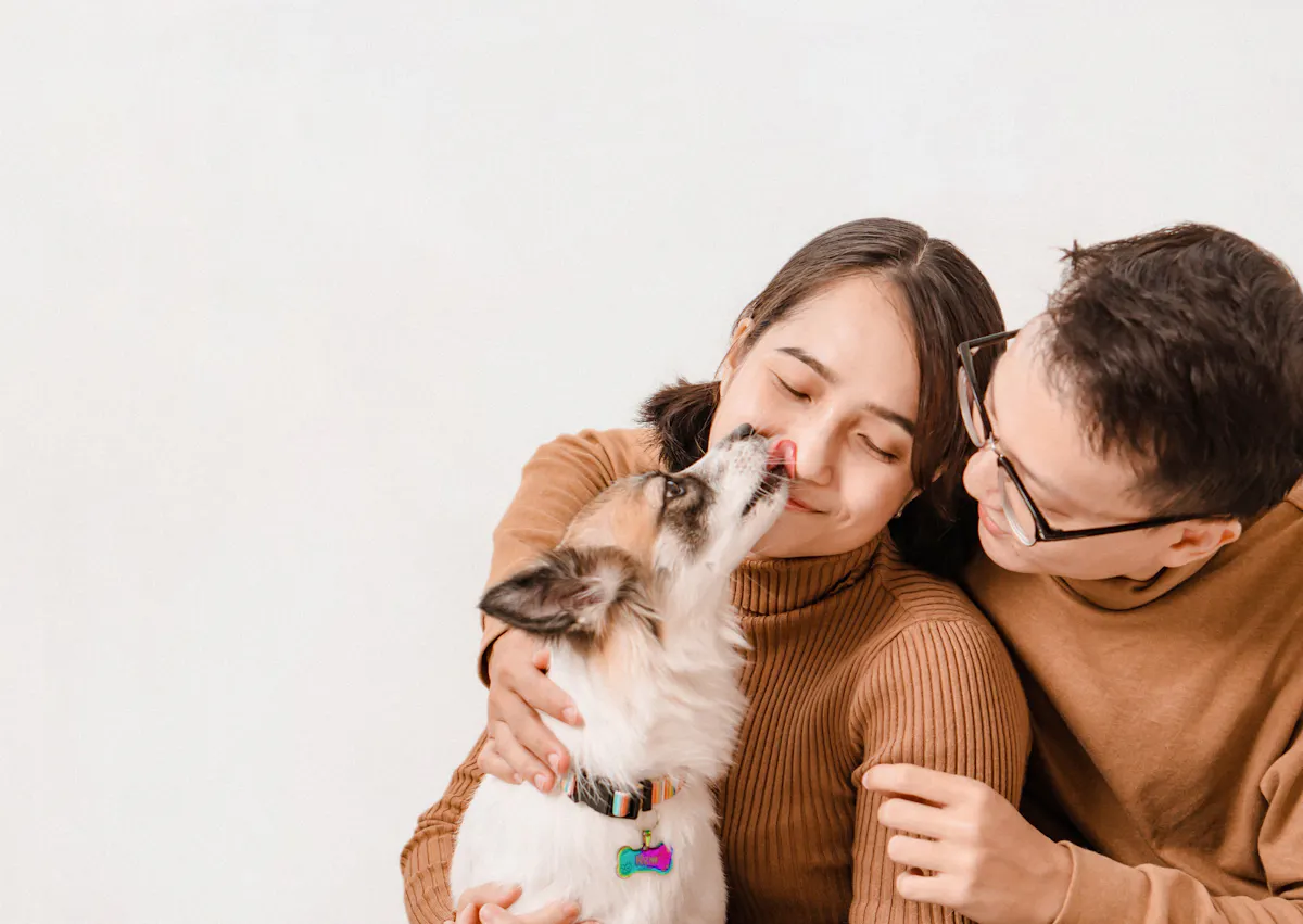 chien qui lèche une femme, un homme les regarde en rigolant