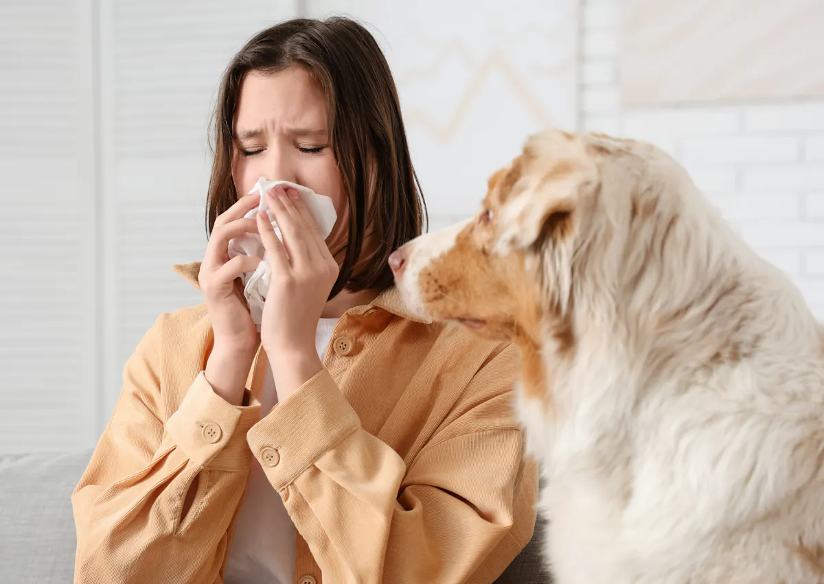 une femme se mouche pendant que son chien la regarde