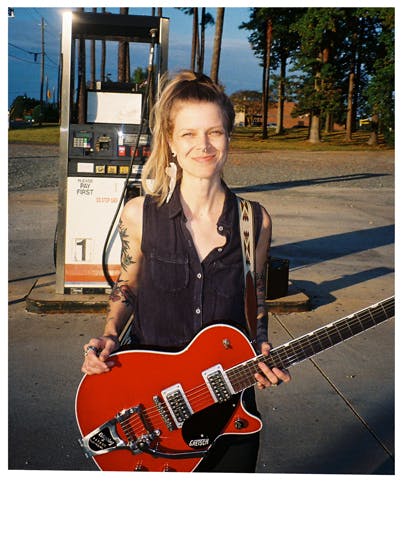 A women at a gas station with a guitar