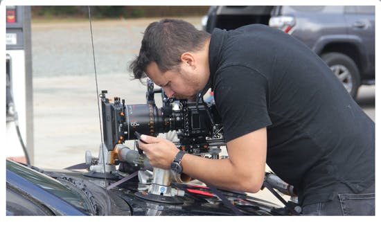 A man placing a camera on the hood of a car
