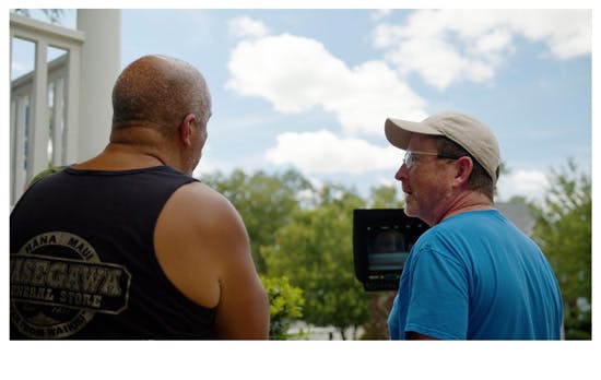 Two men discussing a scene next to a camera