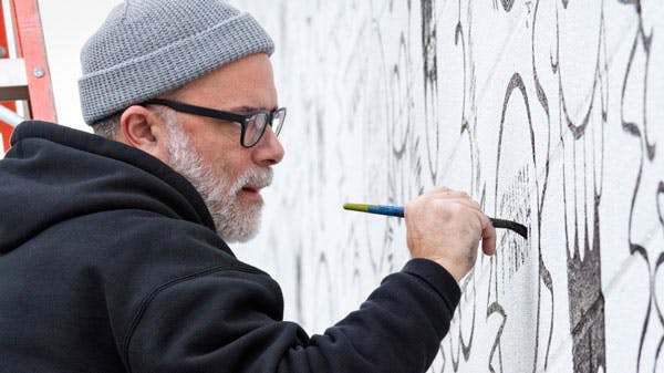 Artist Kevin Lyons painting a mural in Raleigh for Vans x truth