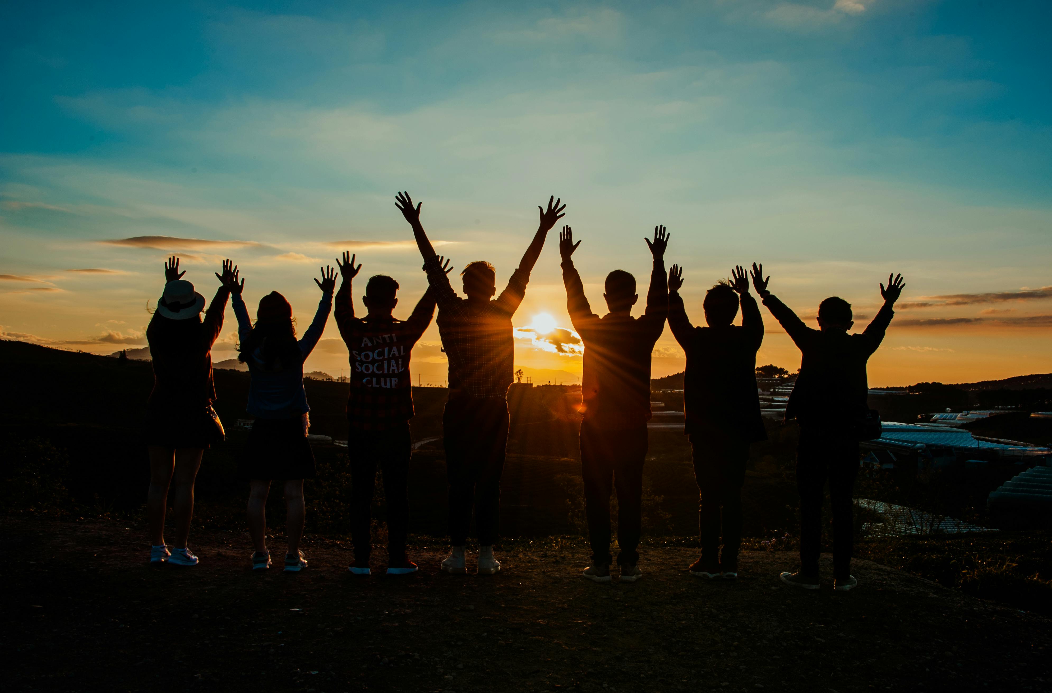 Group of people with hands in the air in the sunset