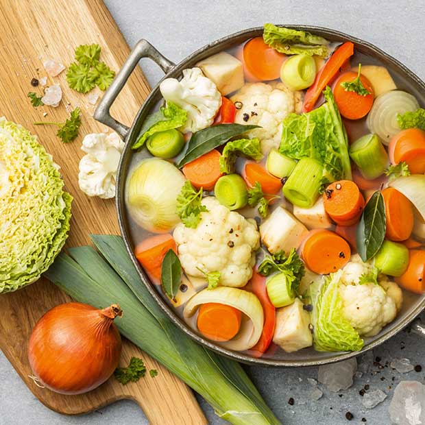 Bild eines Topfes mit Wasser und geschnittenen Karotten, Lauch, Wirz, Sellerie etc.