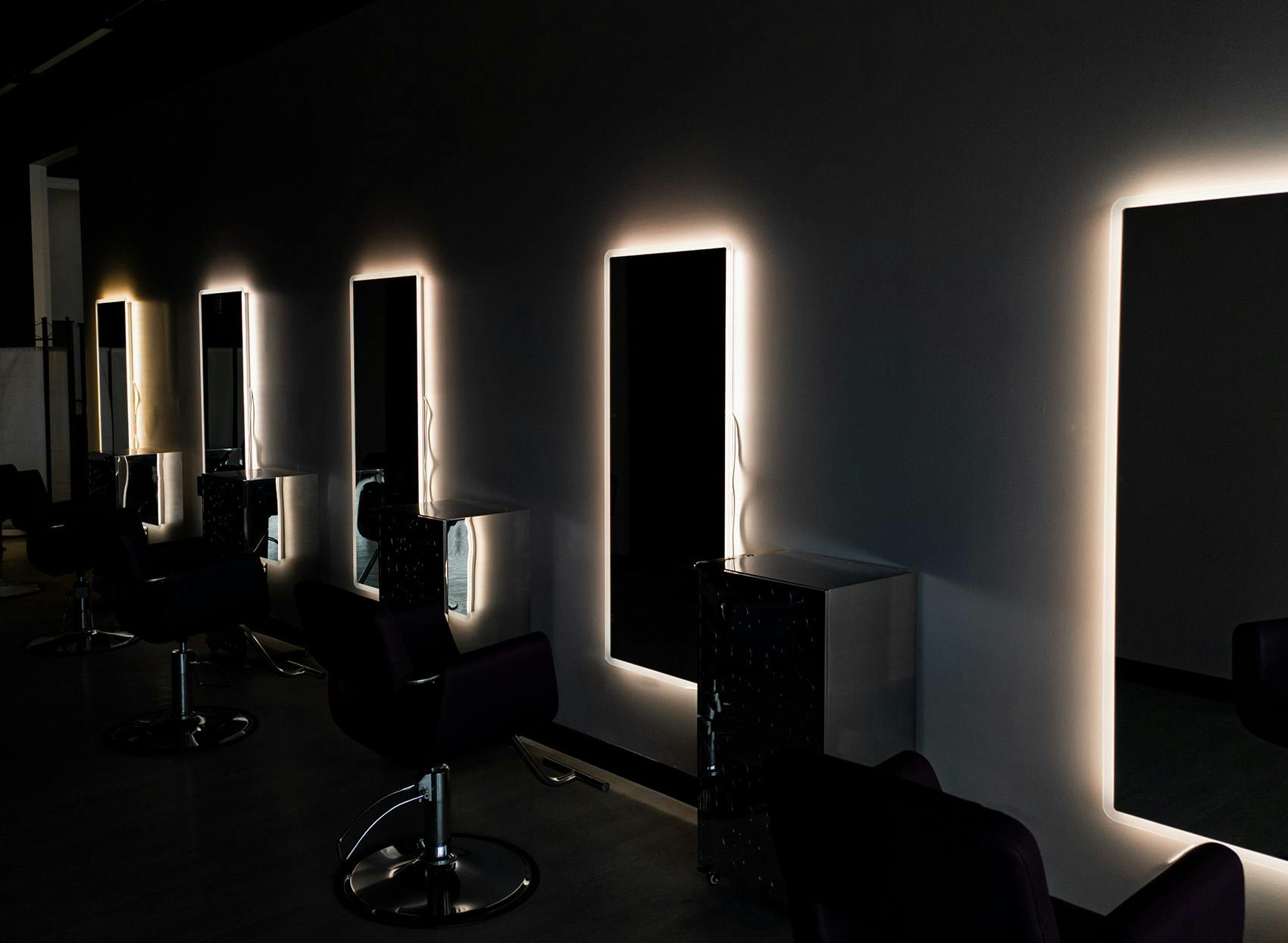 Dark salon with lighting behind mirrors