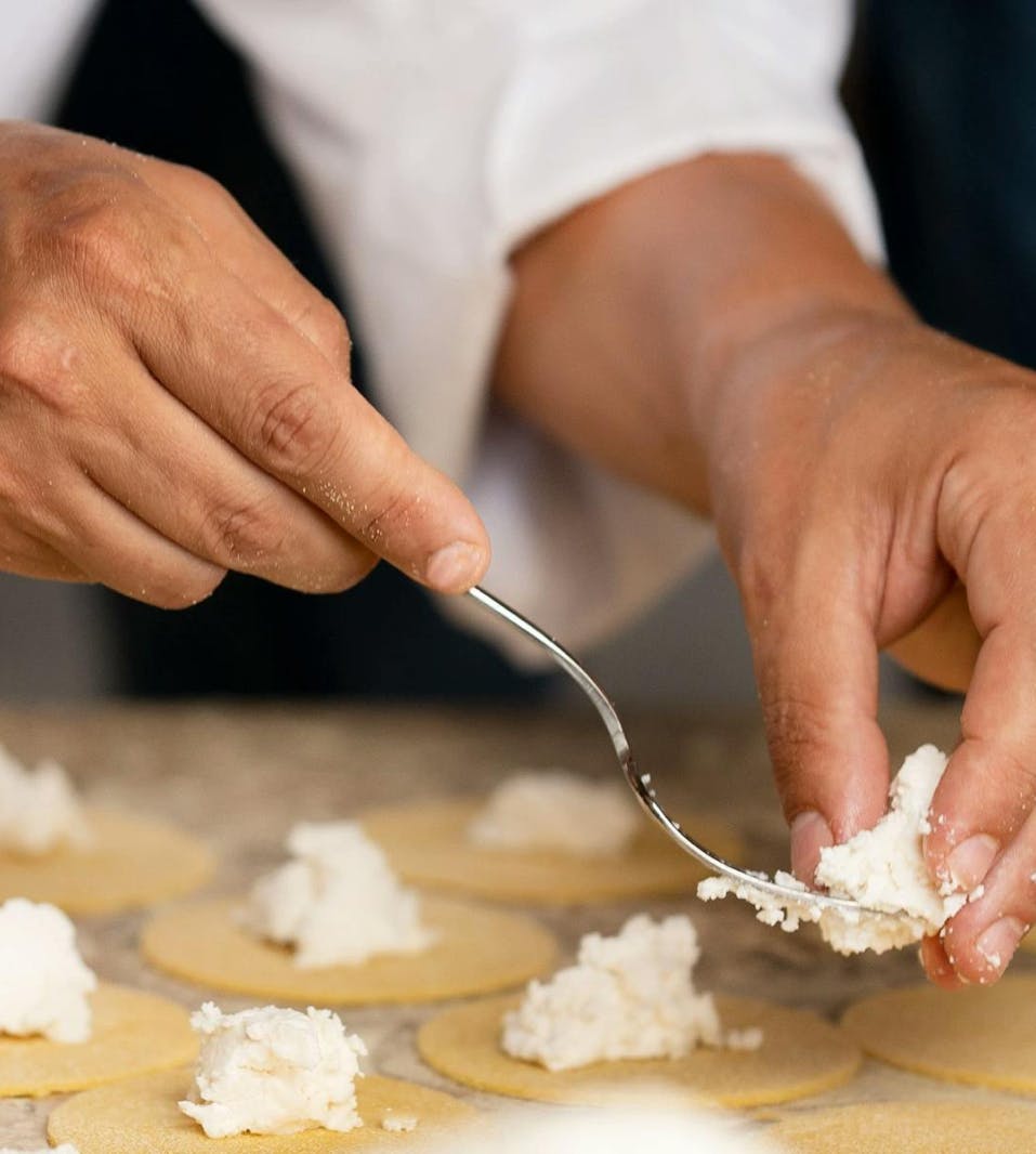 Fingers placing feta cheese on a plate display