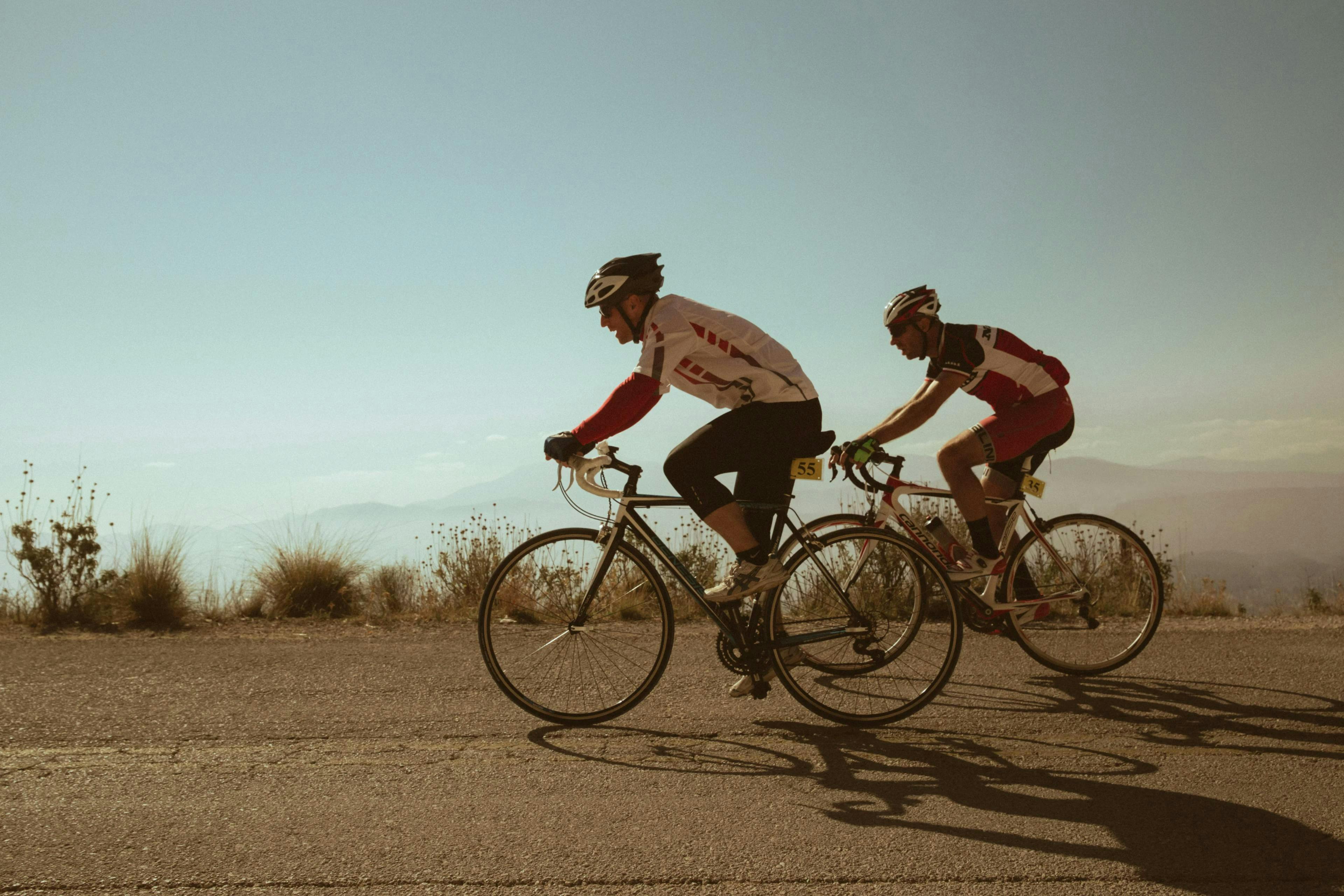 Two men on bikes riding against mountain backdrop